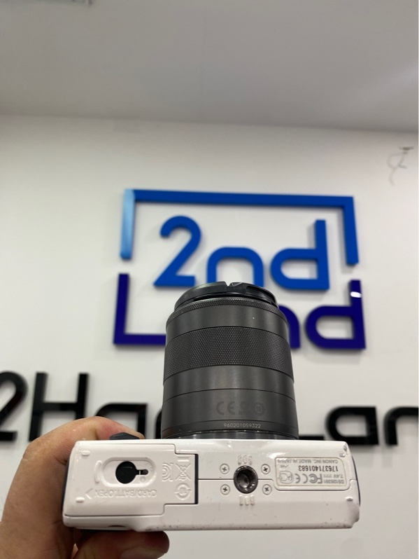 Máy ảnh Canon EOS M - Đời đầu - Màu trắng - Ngoại hình: 97% - Màn ám vàng, xước thân, mất gạt cao su nắp pin - Kèm 1 pin - Sạc - Túi vải - Lens Canon EF-M 18-55mm (xước kính, bể viền lens)